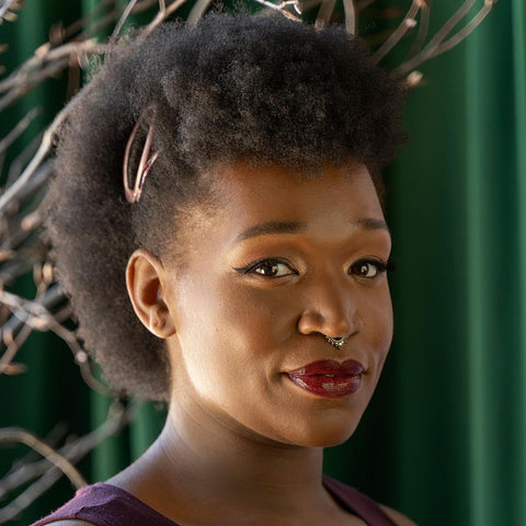 Person with styled hair and red lipstick against a green curtain background