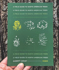 A book titled "A Field Guide to North American Trees" by Loblolly Press, showing tree illustrations and habitat descriptions.